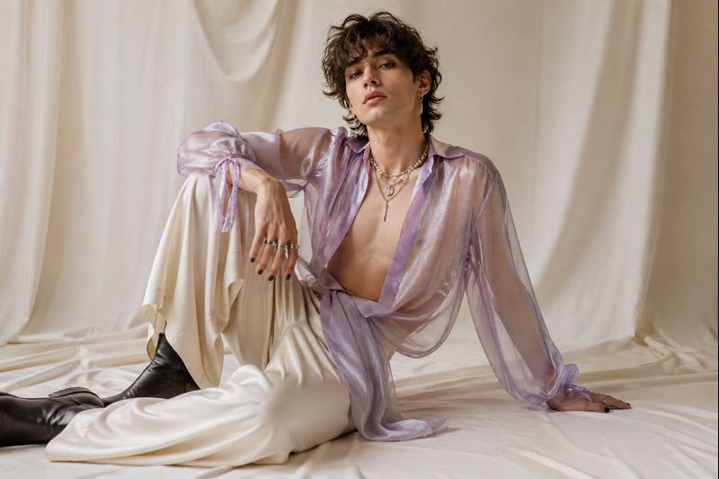 Homme portant un style queer avec vêtements fluides, accessoires visibles et silhouette non genrée