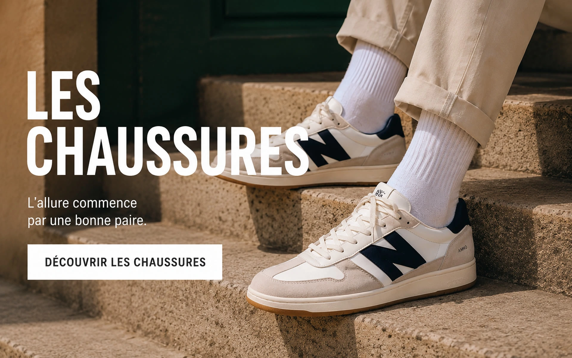Chaussures homme tendance – Sneakers pour tous les hommes Homme assis sur des marches en pierre portant des sneakers blanches et beige dans un style urbain minimaliste.