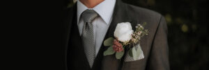 Détail d’un costume de mariage homme gris élégant avec cravate sobre et boutonnière blanche
