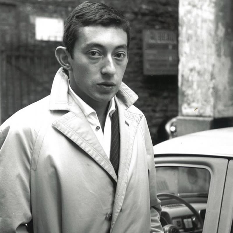 Jeune Serge Gainsbourg portant un trench coat et une tenue élégante classique